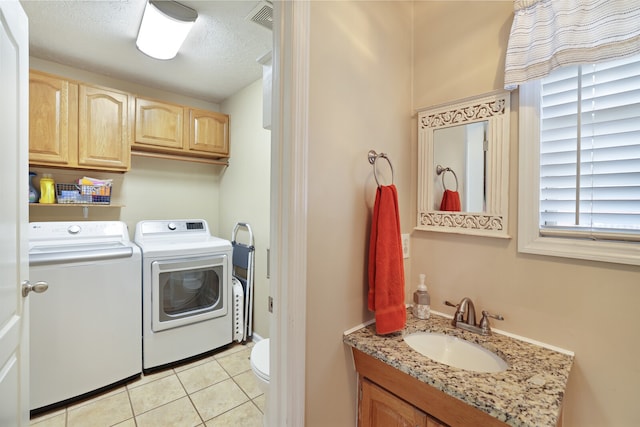 laundry room with a textured ceiling, washing machine and dryer, sink, and light tile patterned flooring