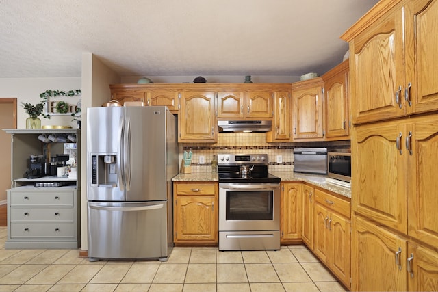 kitchen with light stone counters, light tile patterned floors, appliances with stainless steel finishes, and tasteful backsplash