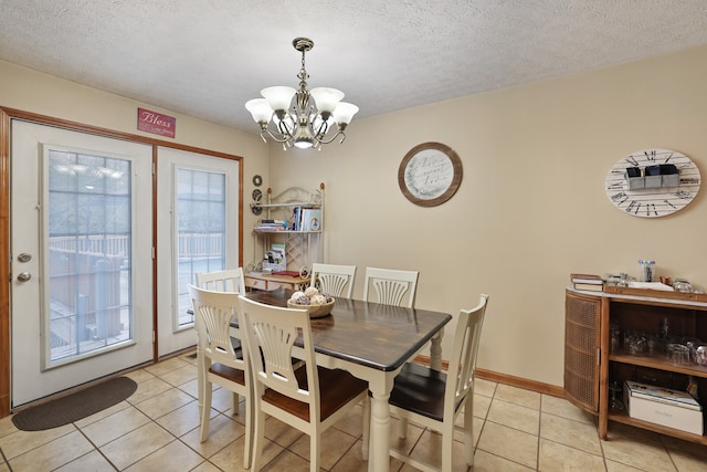 dining area with a textured ceiling, a notable chandelier, and light tile patterned flooring