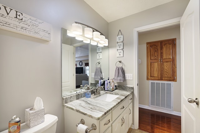 bathroom featuring vanity, toilet, hardwood / wood-style floors, and lofted ceiling