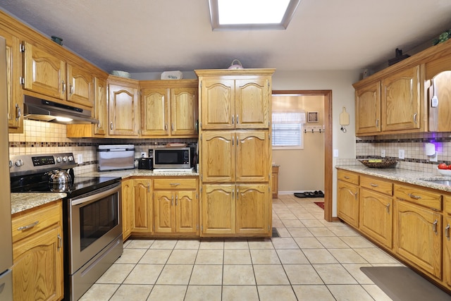 kitchen featuring stainless steel appliances, light tile patterned floors, decorative backsplash, and light stone countertops