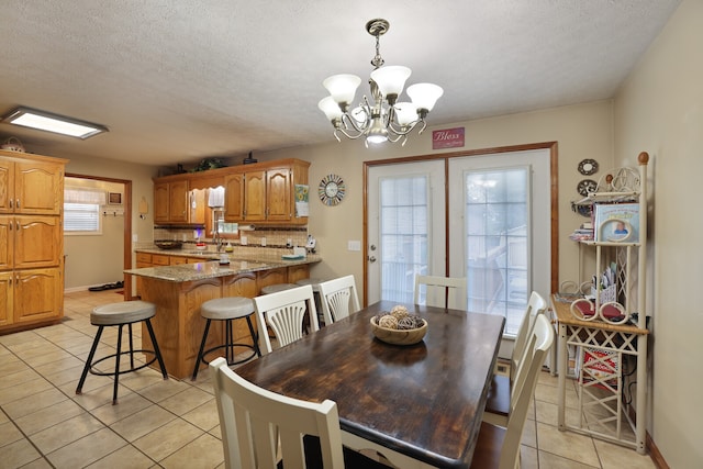 tiled dining space featuring a textured ceiling, plenty of natural light, and a notable chandelier