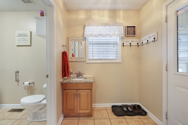 bathroom with a textured ceiling, vanity, toilet, and tile patterned floors