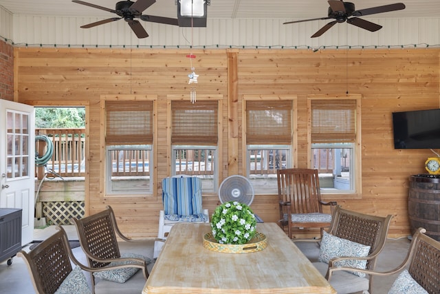 dining room with ceiling fan and wood walls