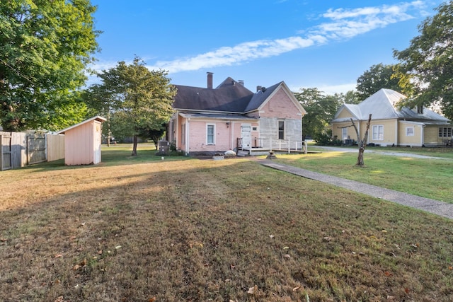 view of front of home with a chimney, fence, a front lawn, and an outbuilding