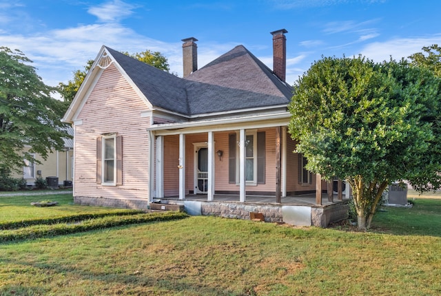 view of front of home featuring covered porch, a front yard, and central AC unit