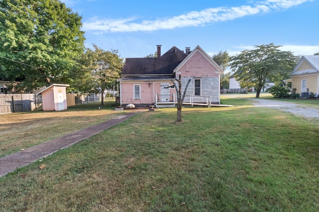 view of front of house with a chimney, a front yard, fence, a shed, and an outdoor structure