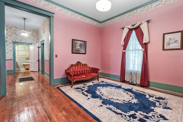 living area with baseboards, hardwood / wood-style floors, and wallpapered walls