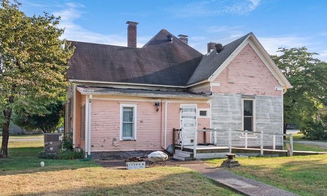 view of front of property featuring a chimney, central AC unit, a front lawn, and a wooden deck