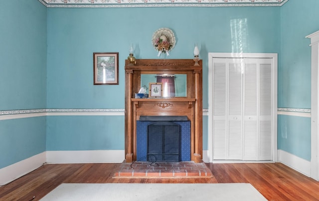 unfurnished living room with a fireplace, baseboards, and wood finished floors