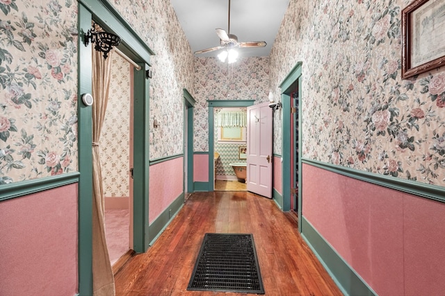 corridor featuring wallpapered walls, visible vents, hardwood / wood-style flooring, and wainscoting