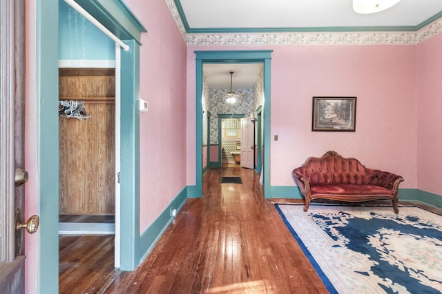 hallway with wood-type flooring, crown molding, and baseboards