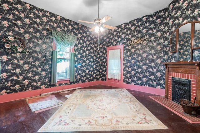 interior space with a ceiling fan, wood finished floors, a brick fireplace, and wallpapered walls