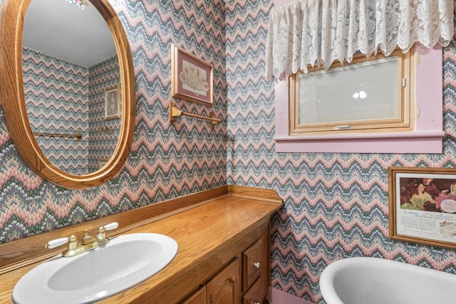 bathroom featuring wallpapered walls, a freestanding bath, and vanity