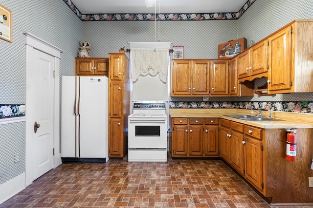 kitchen featuring white appliances, light countertops, a sink, and wallpapered walls