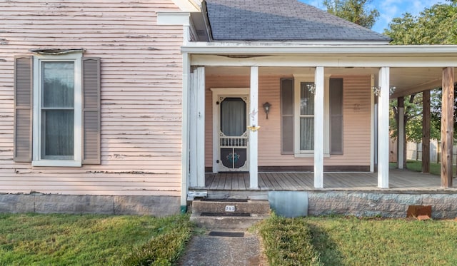 entrance to property featuring a shingled roof and a porch