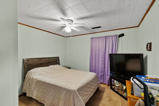 carpeted bedroom with crown molding and ceiling fan