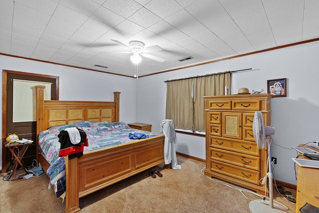 carpeted bedroom featuring ceiling fan and ornamental molding