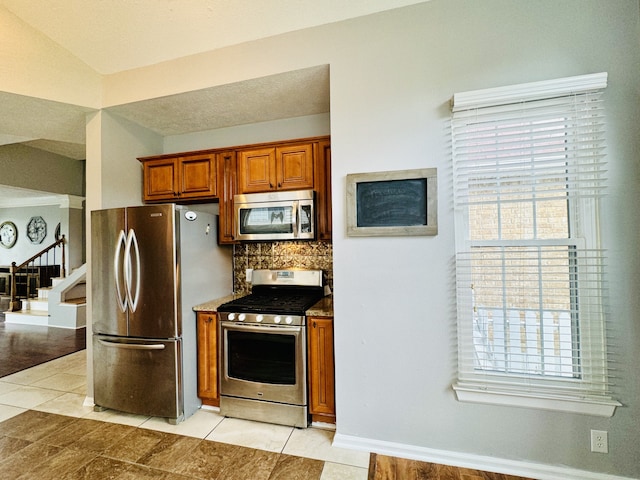 kitchen with appliances with stainless steel finishes, light tile patterned flooring, and tasteful backsplash