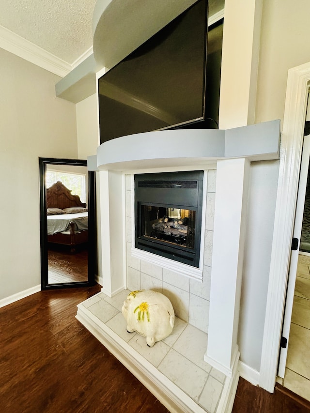 room details featuring hardwood / wood-style flooring, crown molding, a textured ceiling, and a tile fireplace