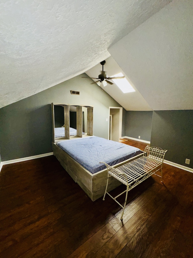 unfurnished bedroom with ceiling fan, a textured ceiling, dark hardwood / wood-style floors, and lofted ceiling with skylight