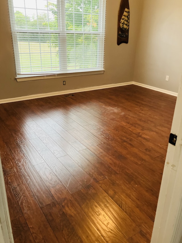 unfurnished room with plenty of natural light and dark wood-type flooring