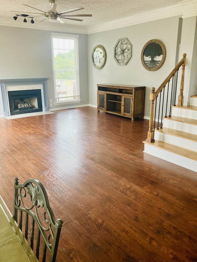 unfurnished living room with ceiling fan, a textured ceiling, dark hardwood / wood-style floors, and ornamental molding