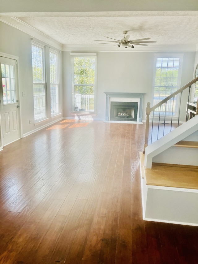 unfurnished living room with a wealth of natural light, ceiling fan, hardwood / wood-style flooring, and a textured ceiling