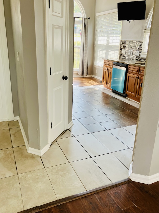 kitchen with backsplash, light tile patterned floors, and stainless steel dishwasher