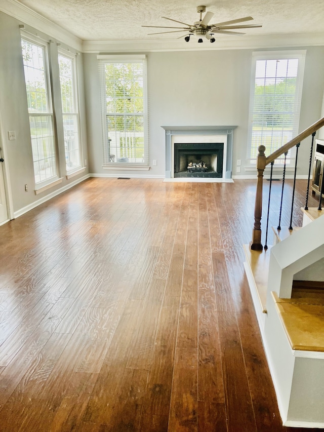 unfurnished living room featuring a textured ceiling, ornamental molding, hardwood / wood-style floors, and ceiling fan