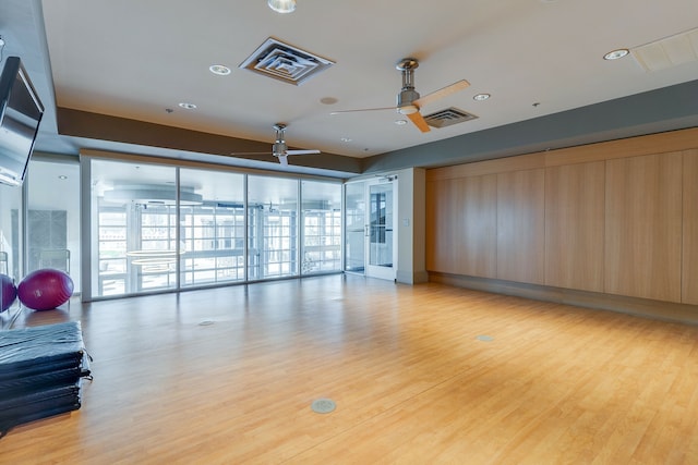 interior space featuring light wood-type flooring, a wall of windows, and ceiling fan