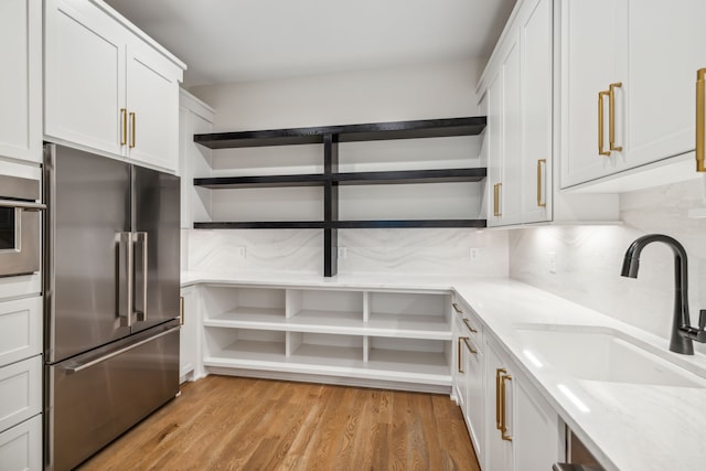 kitchen featuring white cabinetry, light hardwood / wood-style flooring, stainless steel built in refrigerator, and tasteful backsplash