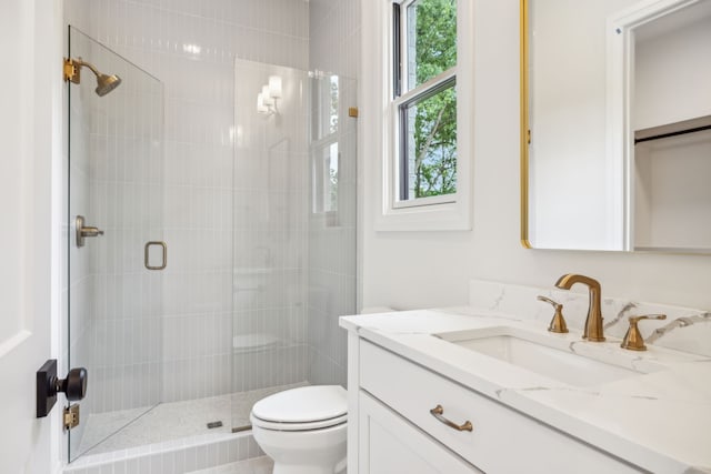 bathroom with a wealth of natural light, vanity, toilet, and walk in shower