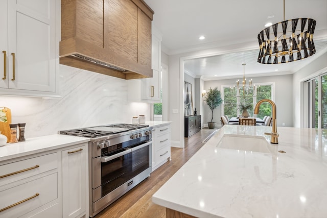 kitchen featuring stainless steel range, an inviting chandelier, white cabinets, and light hardwood / wood-style floors