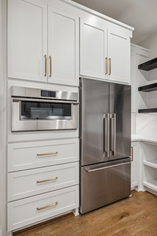 kitchen with stainless steel appliances, hardwood / wood-style flooring, and white cabinets