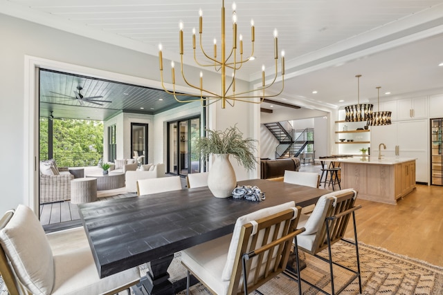 dining room with light wood-type flooring, ceiling fan with notable chandelier, and sink