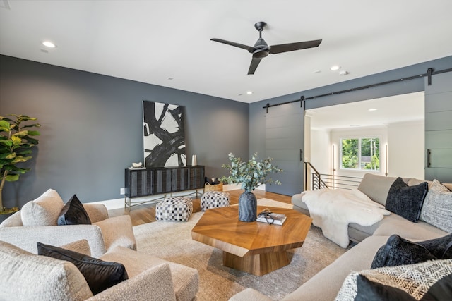 living room featuring a barn door, ceiling fan, and light hardwood / wood-style floors