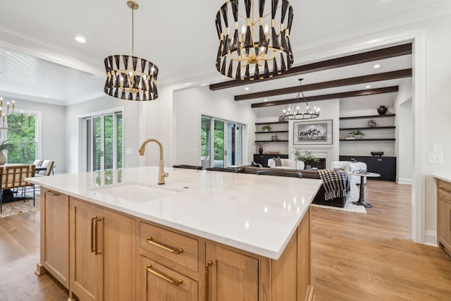 kitchen with light wood-type flooring, a wealth of natural light, a chandelier, and sink