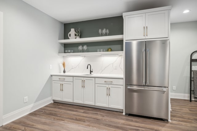 kitchen with stainless steel fridge, hardwood / wood-style floors, backsplash, and white cabinets