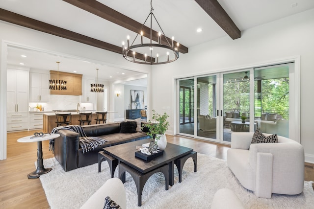 living room with an inviting chandelier, beamed ceiling, and light hardwood / wood-style floors