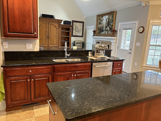 kitchen featuring stainless steel dishwasher, sink, a center island, and dark stone counters