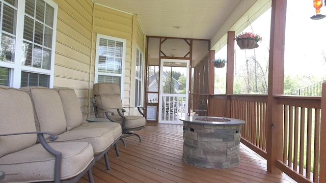 wooden terrace featuring a fire pit and a porch