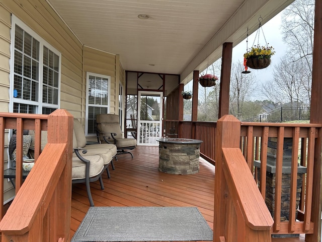 wooden deck featuring covered porch and an outdoor fire pit
