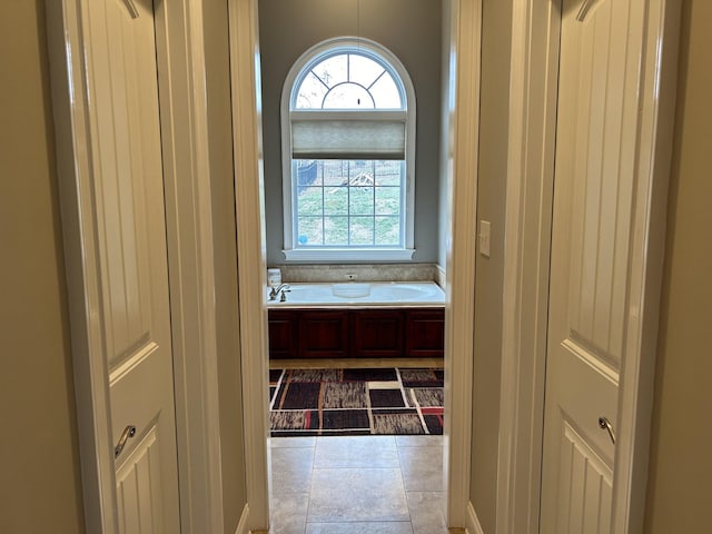 interior space with tile patterned flooring and a garden tub