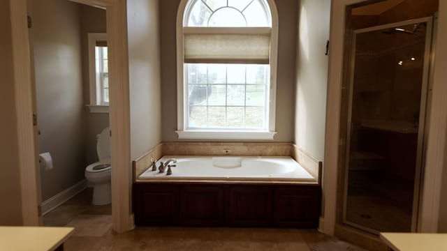full bathroom featuring a garden tub, toilet, and a stall shower