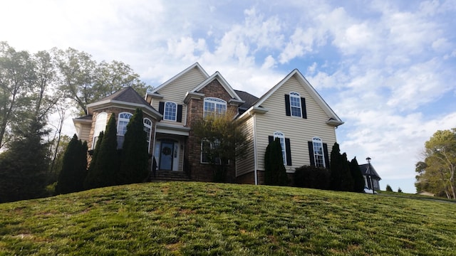 traditional-style home with stone siding and a front yard