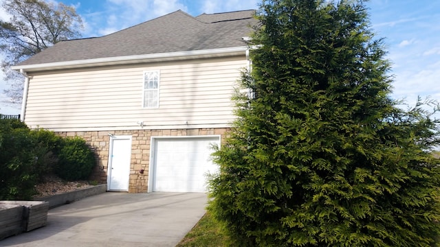 view of home's exterior featuring concrete driveway, a garage, and a shingled roof