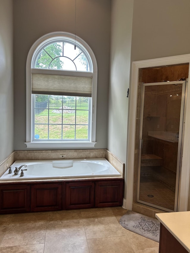 full bath featuring a stall shower, a wealth of natural light, a garden tub, and tile patterned floors