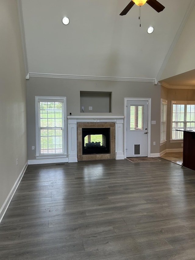 unfurnished living room featuring high vaulted ceiling, crown molding, ceiling fan, baseboards, and a tile fireplace