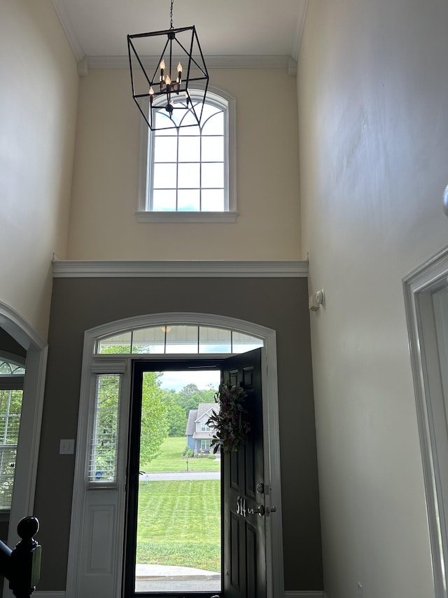foyer entrance featuring a chandelier, crown molding, and a healthy amount of sunlight